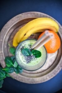 a glass of green smoothie with bananas & oranges