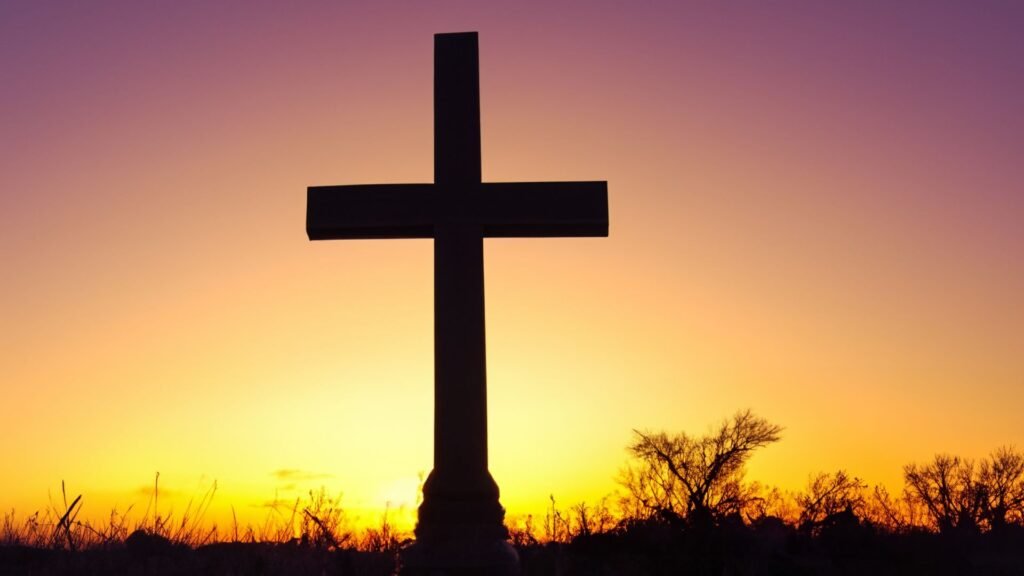 A silhouette of a cross against a vibrant sunset sky, symbolizing faith and offering inspiration for those seeking guidance on how to start reading the Bible.
